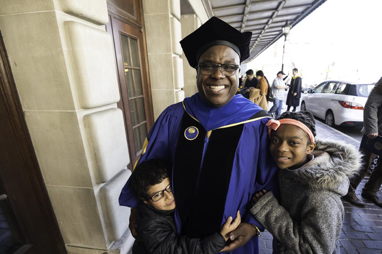 Doctoral degree graduate celebrates with his grandkids after commencement ceremony at Eastman Theatre